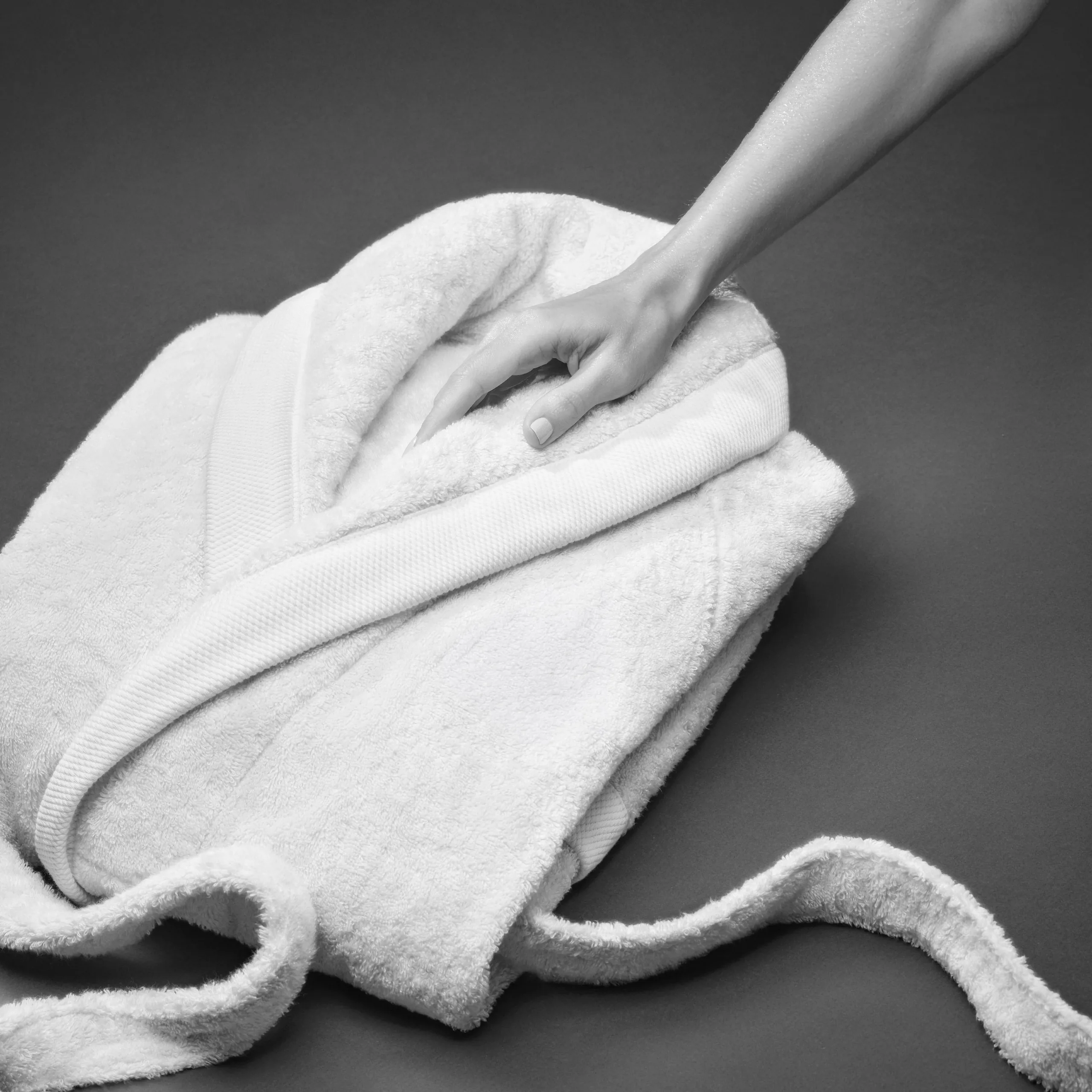 Hand pressing into a folded white Beltrami bathrobe